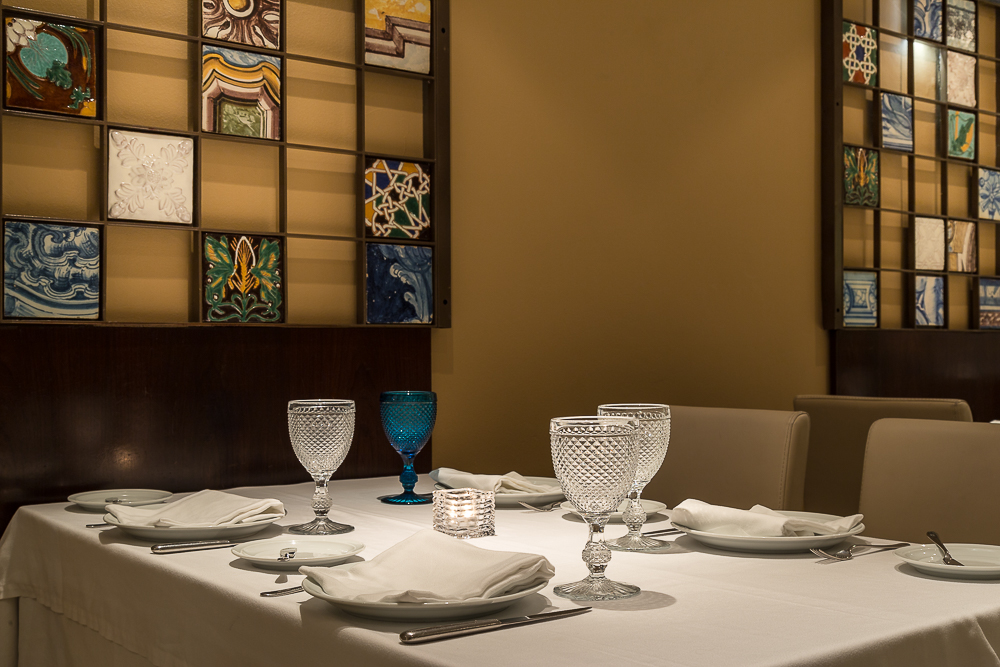 Set dining table beside a blue-and-white azulejo tiled wall